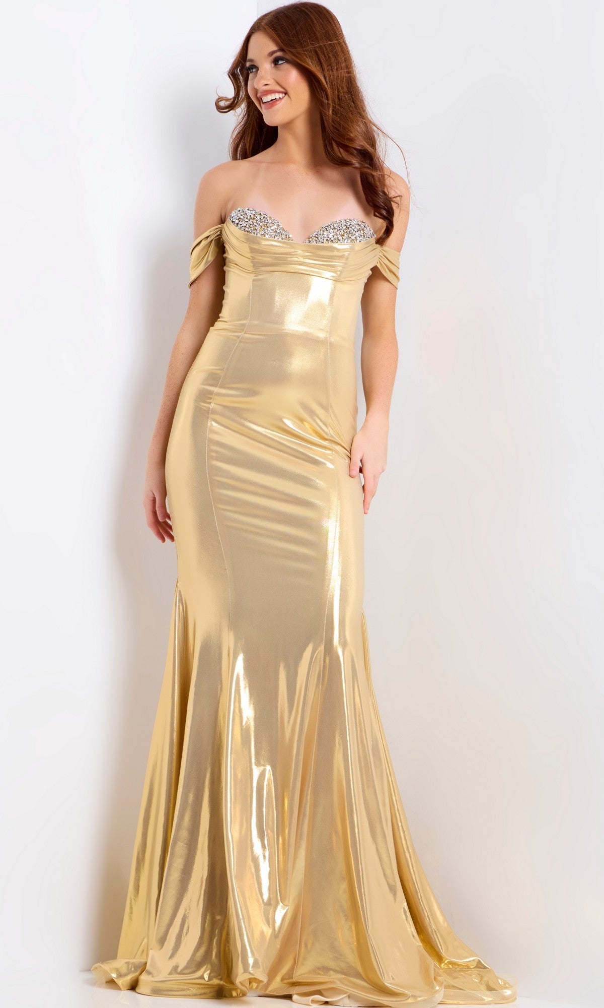 A woman radiates elegance in the Jovani 47062 long prom dress, featuring a gold metallic mermaid silhouette and jeweled bodice detail, as she poses against a plain light background.